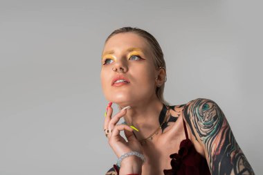 Çekici genç kadın kendine has stilini renkli makyaj ve sanatsal dövmeleriyle sergiliyor..