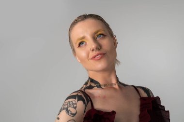 Genç kadın zarif poz veriyor, eşsiz stilini ve sanatsal dövmelerini yumuşak ışıkta sergiliyor..