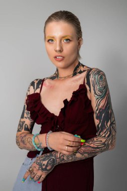 Benzersiz stilini ve canlı dövmelerini vurgulayan genç bir kadının çarpıcı portresi..
