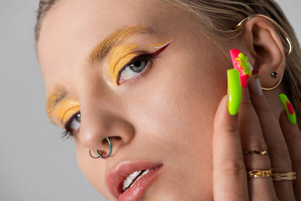 A young woman highlights her fashion sense through bold makeup and colorful nails in a close up.
