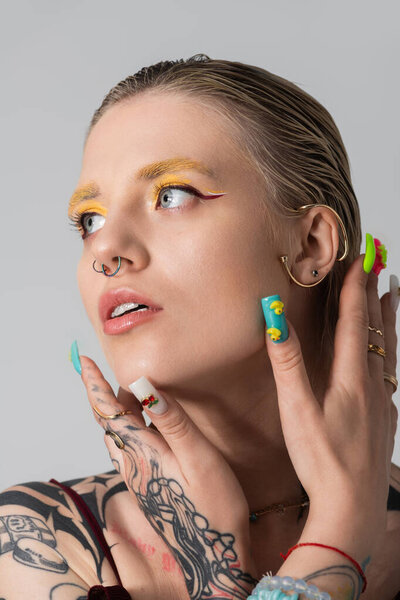 Young woman showcases creative makeup and colorful nails in a stylish setting.