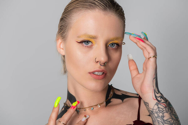 Elegant youth displays unique style and confident expression with bold makeup and accessories