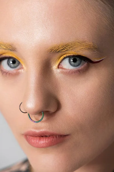 Kendine güvenen genç bir kadın cesur makyajı ve eşsiz piercingleriyle hava atıyor..