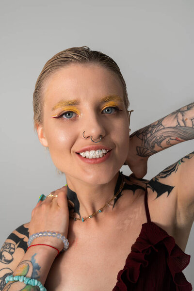 A beautiful young woman showcases her artistic style with colorful makeup and striking tattoos.
