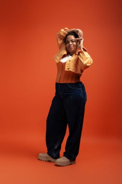 Şık, iri yarı, Afro-Amerikan bir kadın, güz modasına uygun şekilde poz veriyor..