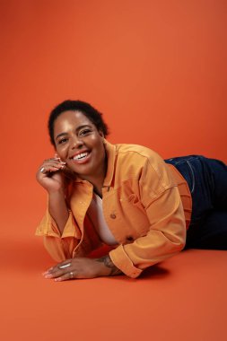 Kendinden emin, iri yarı siyahi bir kadın moda bir sonbahar kıyafetinin modelliğini yapıyor, vücut pozitifliğini kutluyor..