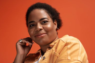 Şık, iri yarı, siyahi bir kadın, sonbahar trendlerini sergileyerek bir stüdyoda güven içinde poz veriyor..