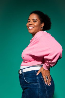 Kendinden emin, iri yarı, siyahi bir kadın stüdyoda moda bir sonbahar kıyafeti içinde poz veriyor..