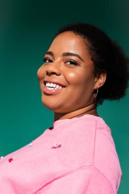 Parlak stüdyo, kendine güvenen, iri yarı, Afro-Amerikan bir kadının moda sonbahar kıyafetlerini görüntüledi..