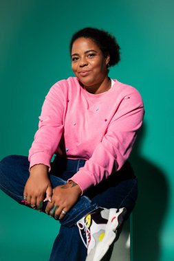 Kendine güveni tam ve cüsseli bir kadın eşsiz bir sonbahar elbisesi içinde poz veriyor, ışık saçan bir tarz ve pozitiflik..