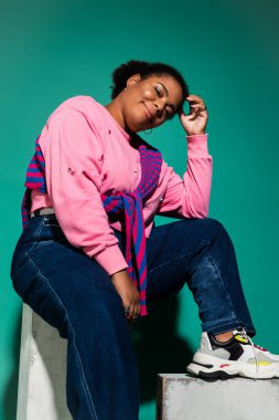 Kendinden emin ve cüsseli bir kadın şık sonbahar kıyafetiyle canlı bir stüdyoda poz veriyor..