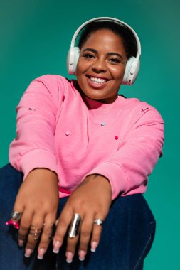 Bu şık ve cüsseli kadın renkli bir stüdyoda poz verirken modaya uygun bir sonbahar kıyafeti sergiliyor..