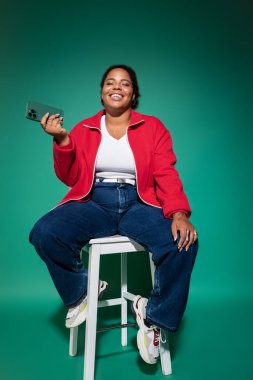 Tarz sahibi, iri yarı, Afro-Amerikan kadın, modaya uygun bir sonbahar elbisesi giyiyor..