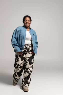 Kendinden emin ve cüsseli bir kadın, stüdyo ortamında vücut pozitifliği saçan modaya uygun bir sonbahar kıyafeti sergiliyor..