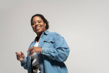 Kendinden emin, iri yarı, siyahi bir kadın şık bir sonbahar kıyafetiyle evde gülümsüyor..