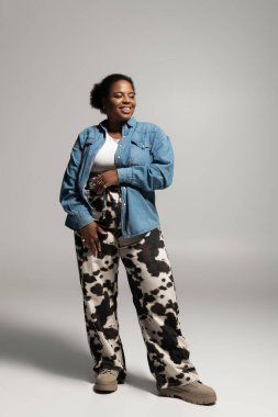 Kendine güvenen iri yarı siyahi bir kadın yaratıcı bir stüdyoda şık bir sonbahar kıyafeti modelliyor..