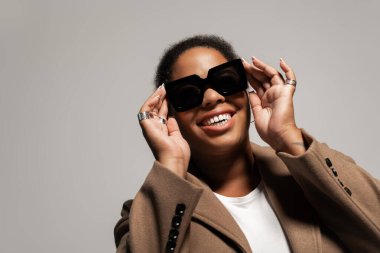 Kendinden emin ve cüsseli bir kadın, bir stüdyoda gülümserken şık sonbahar kıyafetini sergiliyor..