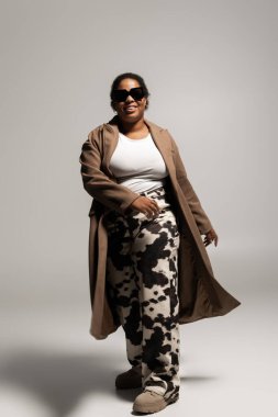 Kendine güvenen, iri yarı bir kadın şık bir stüdyoda sonbahar modasına kucak açar, tarz ve çeşitlilik yayar..