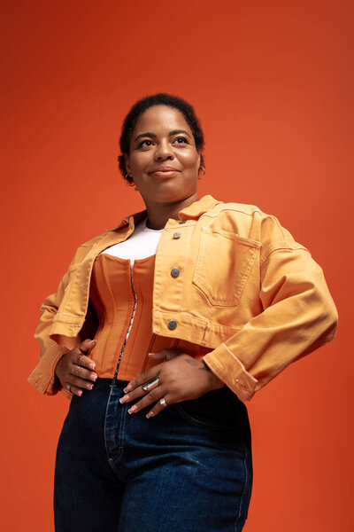 Уверенная женщина моделирует модный осенний наряд, празднуя моду и разнообразие в студии.