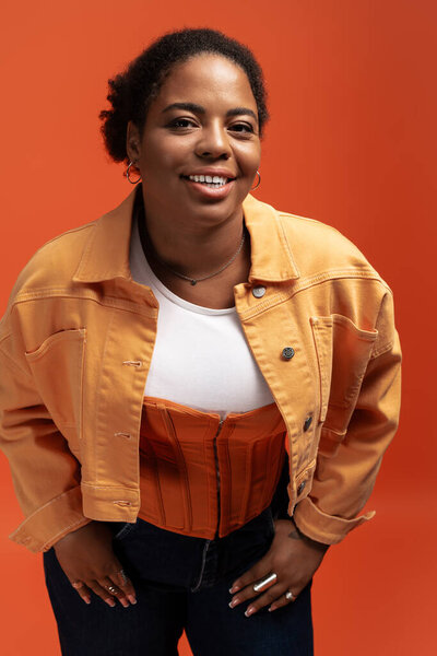 Уверенная в себе африканская женщина plus size демонстрирует триумфальную осеннюю экипировку в яркой студии.