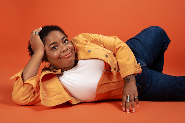A plus size african american woman lounges in a trendy autumn outfit, expressing body positivity.