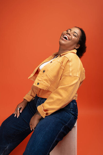 Радостный плюс размер афроамериканка демонстрирует свой модный осенний наряд в студии.