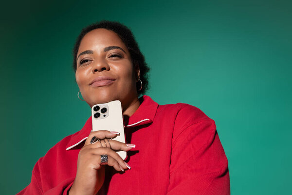 A confident plus size African American woman poses in a trendy autumn outfit, smiling.