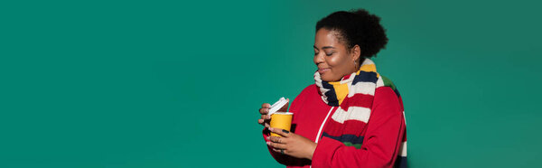 A fashionable plus size african american woman sips a warm drink while wearing cozy autumn attire, banner