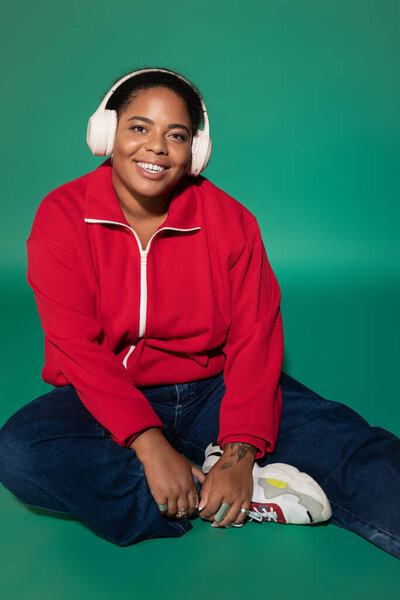 A confident plus size woman enjoys the autumn season in a trendy outfit, smiling warmly.