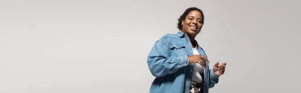 Stylish plus size woman poses confidently in a trendy autumn outfit in a studio with soft lighting, banner