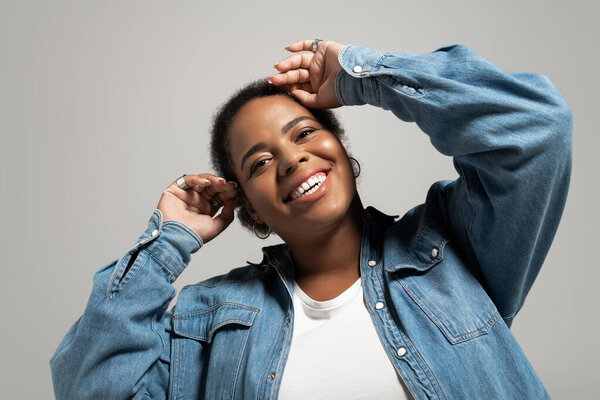 A confident plus size african american woman showcases a trendy autumn outfit in a bright studio.