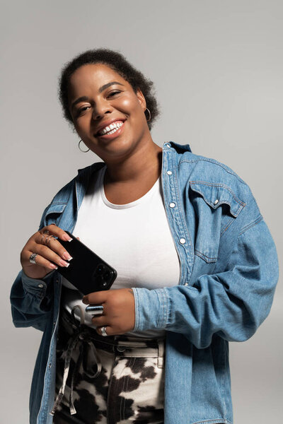 Плюс размер женщина носит модный осенний наряд, улыбаясь в студии, празднуя положительный настрой тела.