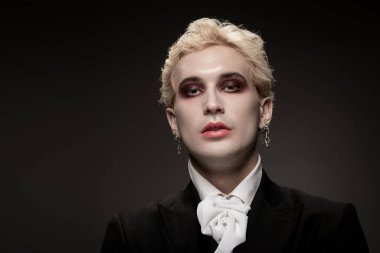 Genç bir adam çarpıcı Cadılar Bayramı kostümünü ve dramatik makyajını karanlık bir ortamda sergiliyor..