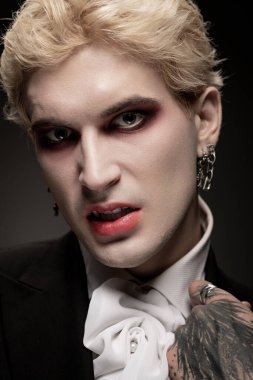 Yakışıklı bir genç gururla destansı, detaylı bir Cadılar Bayramı kostümü ve kalın bir makyaj giyer..