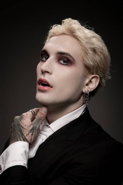 Genç yakışıklı bir adam etkileyici makyajı ve saçı olan destansı bir Cadılar Bayramı kostümü sergiliyor..