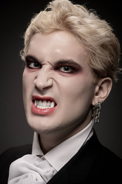 Молодой человек демонстрирует эпический костюм на Хэллоуин со смелым макияжем и свирепым выражением лица.