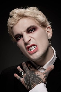 Genç adam yoğun makyaj ve kostümle Cadılar Bayramı ruhunu somutlaştırıyor, sert bir poz veriyor..