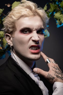 Genç bir adam çarpıcı bir Cadılar Bayramı kostümü sergiliyor cesur makyajı ve eşsiz aksesuarlarıyla.