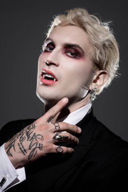 Genç adam etkileyici bir Cadılar Bayramı kostümü sergiliyor. Kalın makyaj ve şık aksesuarları var..