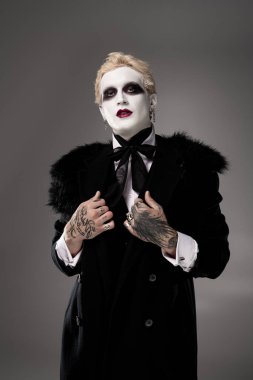 Göz alıcı genç bir adam, dikkat çekici güzellikte bir Cadılar Bayramı kostümü giyer..