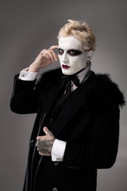 Yakışıklı genç adam etkileyici bir Cadılar Bayramı kostümü giyiyor, kendine güveni ve yaratıcılığı var..