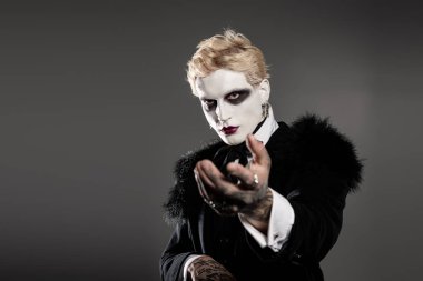 Genç adam etkileyici Cadılar Bayramı kostümü ile büyüleyici makyaj ve zarif kıyafetlerle