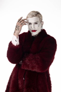 Joker gibi giyinmiş yakışıklı adam Cadılar Bayramı kutlamaları için cesur bir kostüm giyiyor..