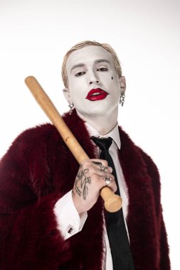 Genç bir adam etkileyici Joker kostümünü ahşap bir sopayla sergiliyor..