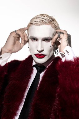 Genç bir adam cadılar bayramı için cesur makyajı ve şık kıyafetleriyle Joker kostümünü gösteriyor..