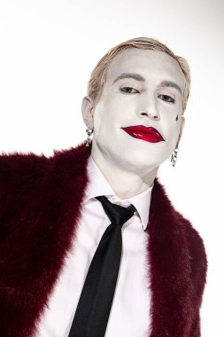 Genç bir adam sanatsal makyajını ve kıyafetlerini vurgulayan ayrıntılı bir Joker kostümü sergiliyor..