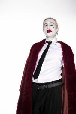 Joker gibi giyinmiş genç adam çarpıcı bir Cadılar Bayramı kostümü ve kendine güvenen bir pozla büyülüyor..