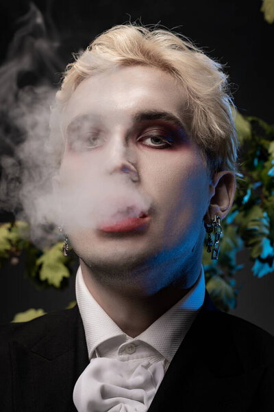 A stylish young man enjoys Halloween in a stunning costume while smoke swirls around him.