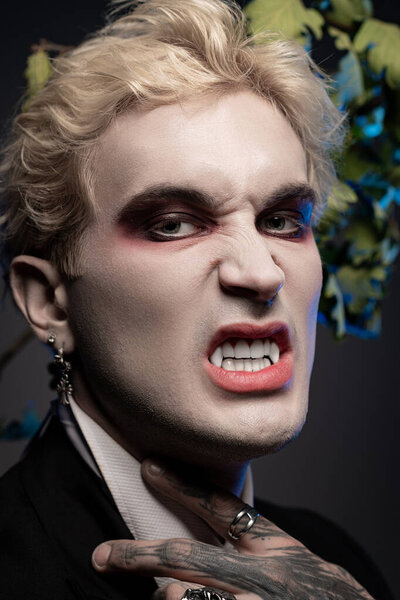 A handsome young man in a striking Halloween costume shows fierce energy with makeup and pose.