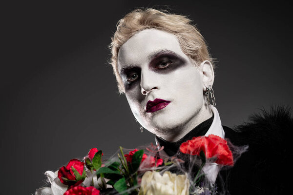 Молодой человек демонстрирует эпический костюм на Хэллоуин, выделенный ярким макияжем и яркими розами.